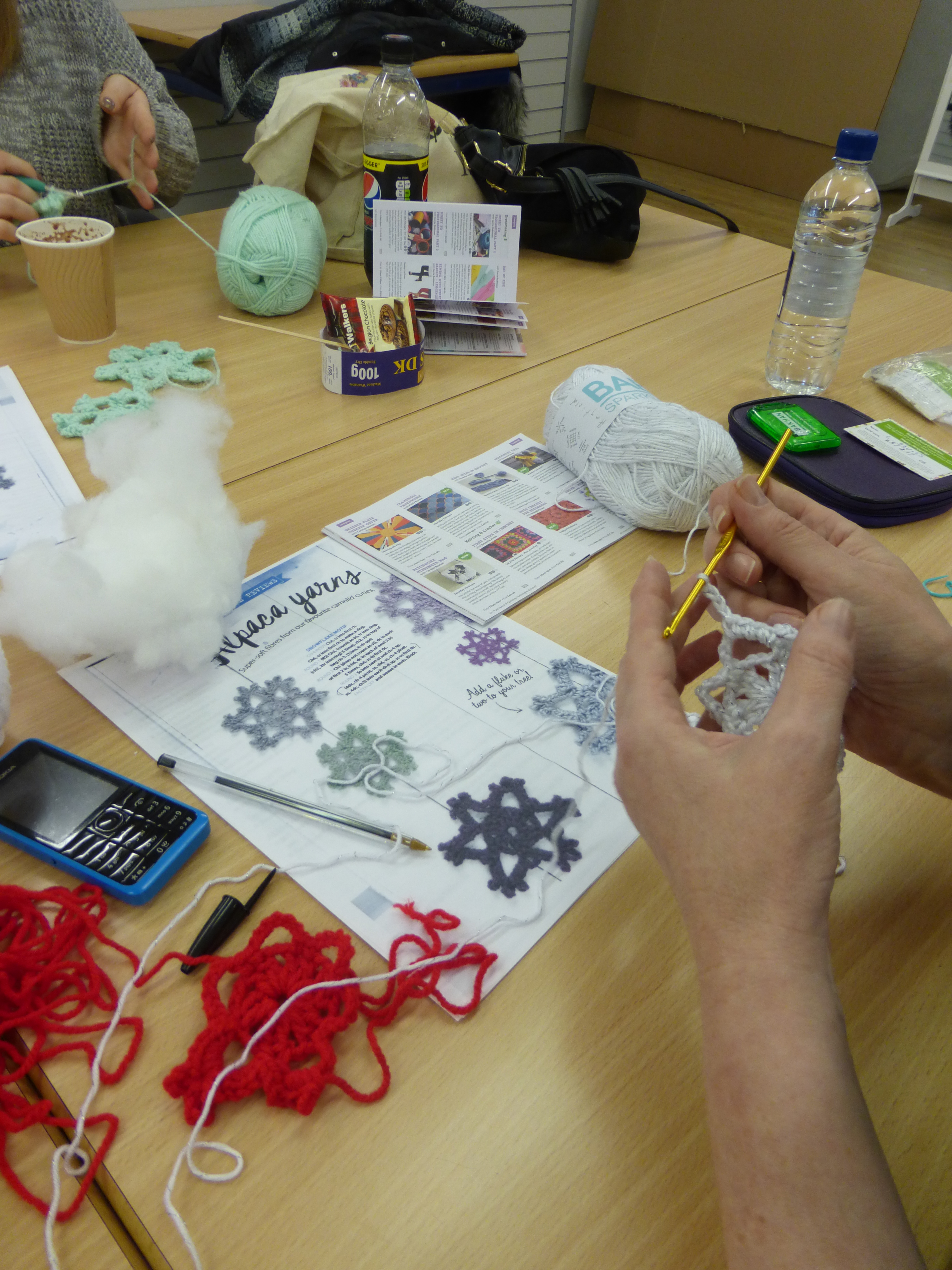 pair of hands crocheting a snowflake at a crochet class