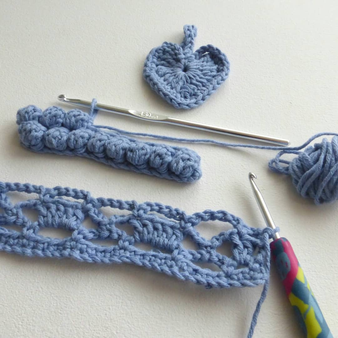 crochet heart, crochet hook with bobble stiches on, crochet hook with crochet stiches on, all in blue yarn.
