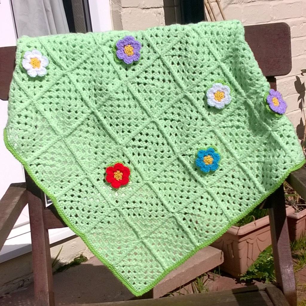 green crochet granny square blanket with 6 crochet flowers attached